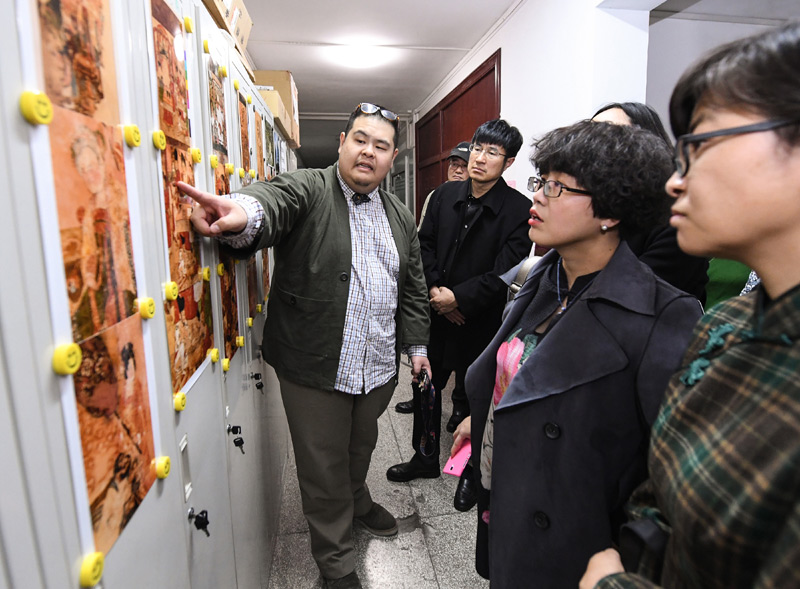 4月2日，科研人员（左一）向与会专家学者介绍纺织考古研究成果。