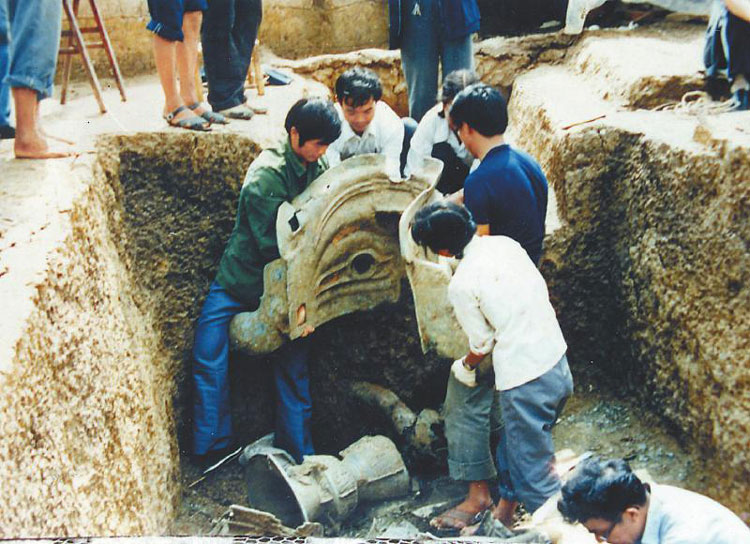 1986年三星堆祭祀坑发掘现场,考古人员正在把青铜面具抬出祭祀坑.