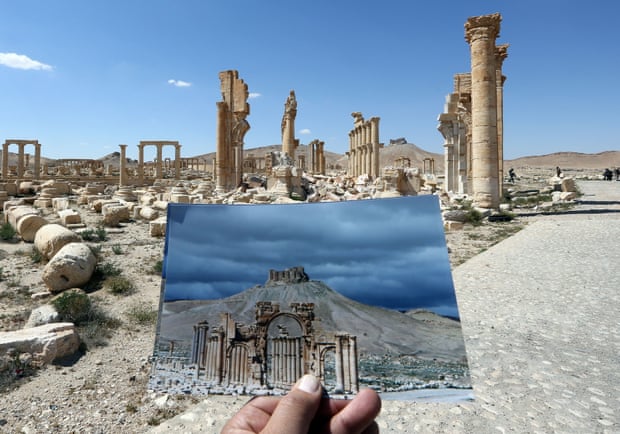 2016年，在被“伊斯兰国”摧毁的巴尔米拉凯旋门前拍摄的照片，其手持的是2014年拍摄于同一地点的风景的照片。