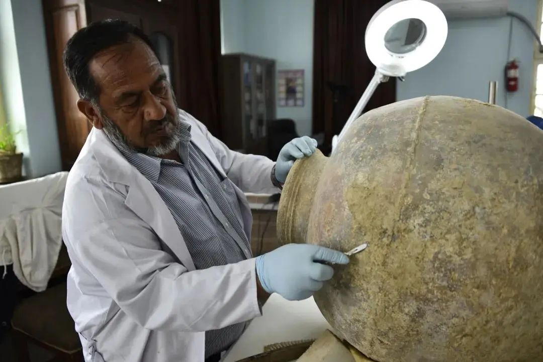 博物馆修复人员正在清理艾纳克遗址出土的陶罐  ©敦煌研究院