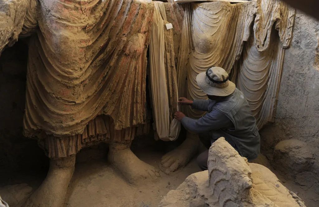 2010年，一名阿富汗考古学家在洛加尔省东部梅斯·艾纳克的一座古老寺院里考察佛像。 SHAH MARAI/AGENCE FRANCE-PRESSE VIA GETTY IMAGES  