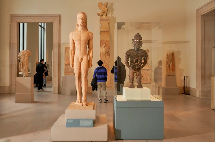 “前进的动力”部分展出的一对艺术品。左：大理石的青年雕像，希腊，约公元前590 - 580年；右：力量塑像，中非地区（来自刚果民主共和国），19世纪中期。（摄影：Seth Caplan）